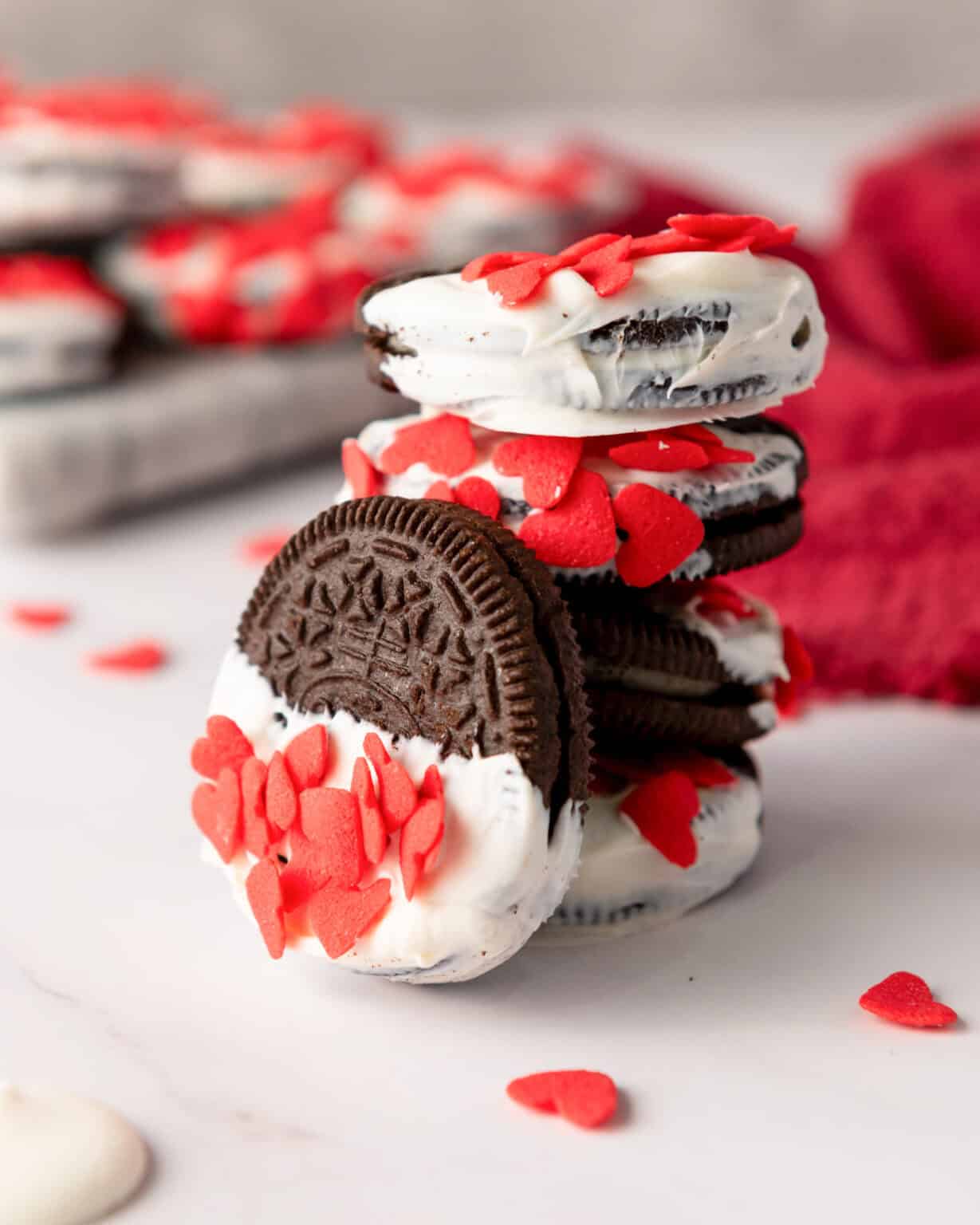 a stack of white chocolate dipped sandwich cookies with red sprinkles on top