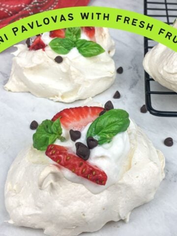 text overlay "mini pavlovas with fresh fruit" and a picture of three small small pavlovas with strawberries and blueberries