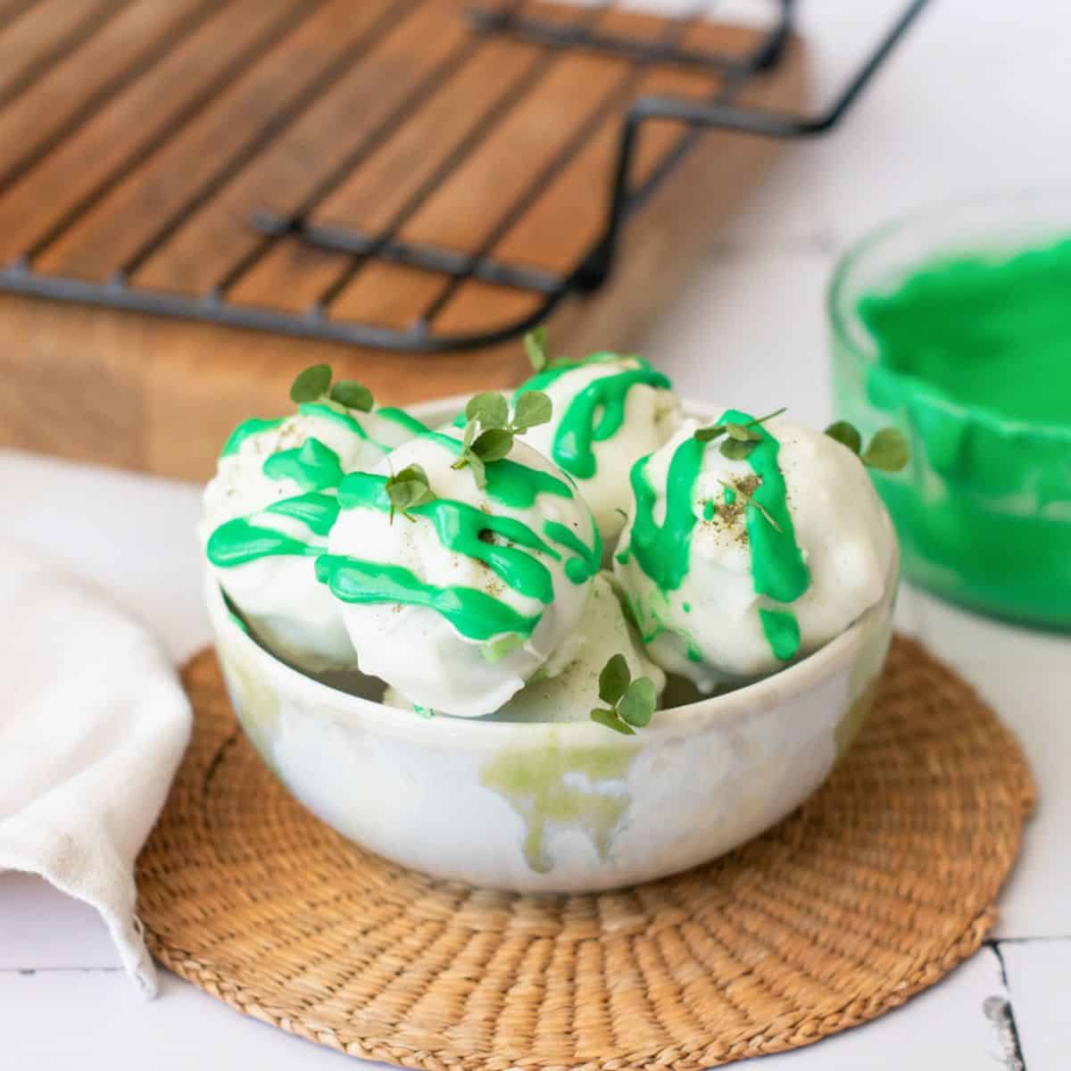 a bowl with white and green chocolate drizzled no bake gluten free truffles 