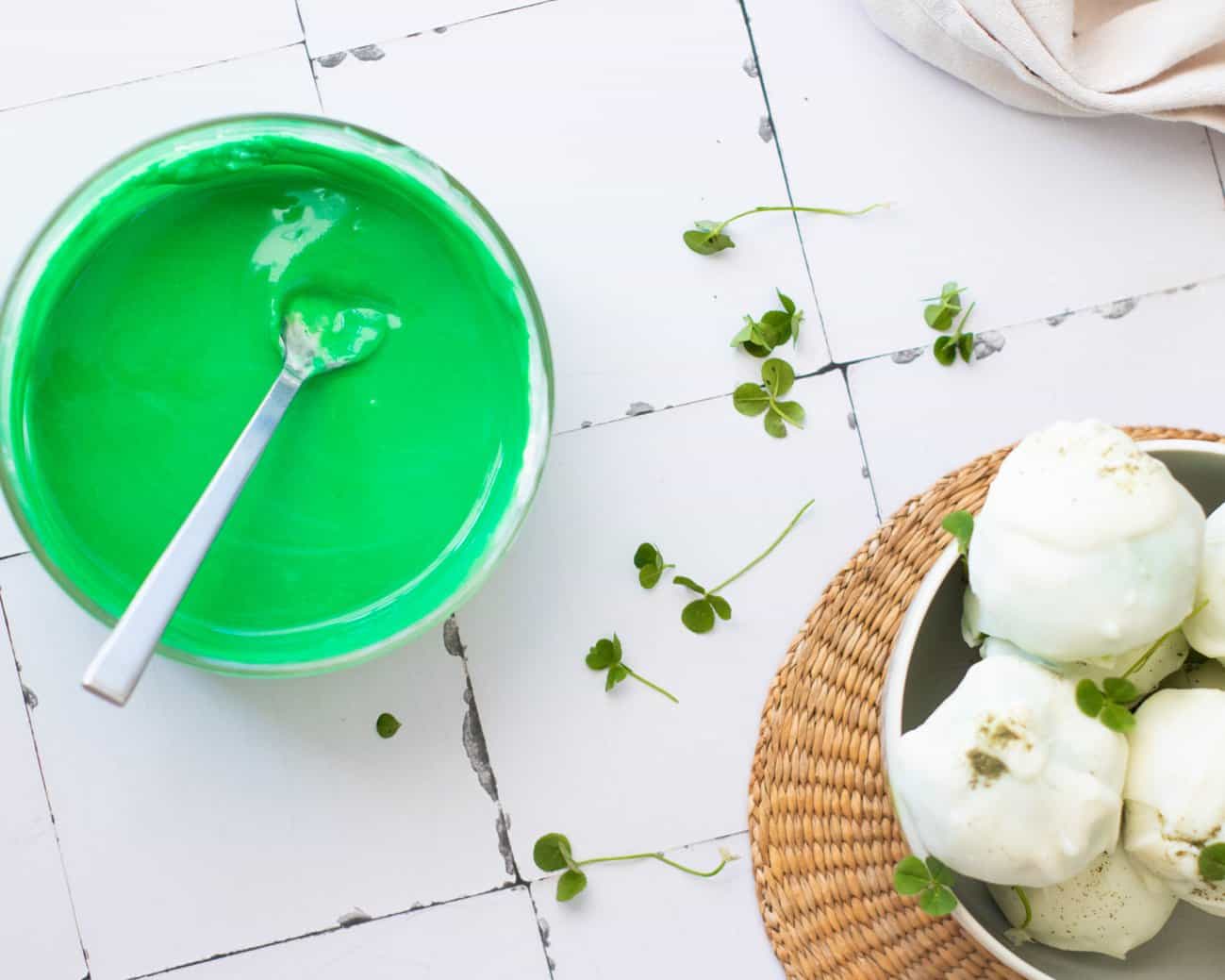 mixing green food coloring into white chocolate to make a drizzle