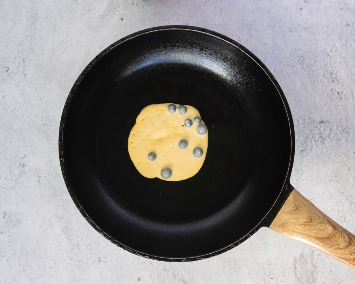 cooking a gluten free blueberry pancake in a pan