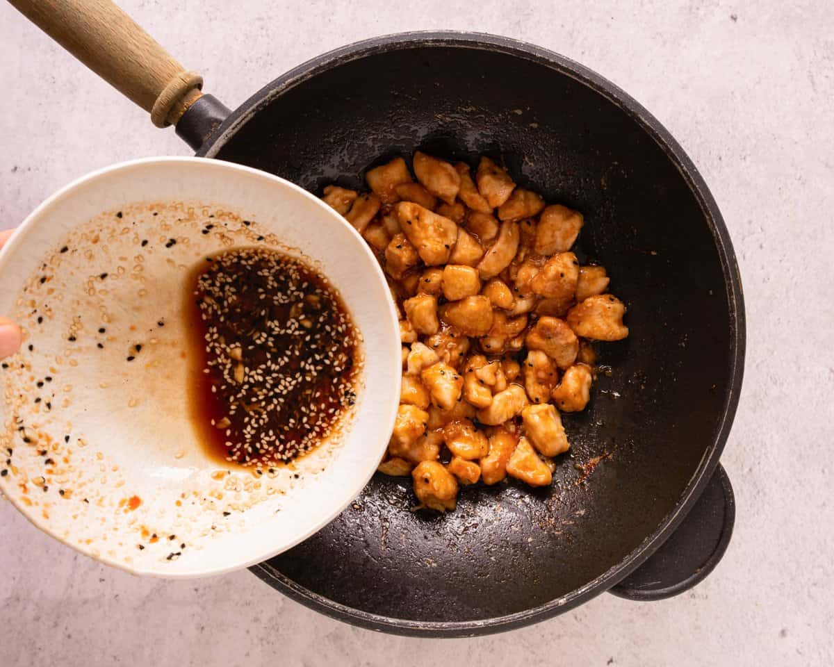 adding sauce to a skillet with chicken