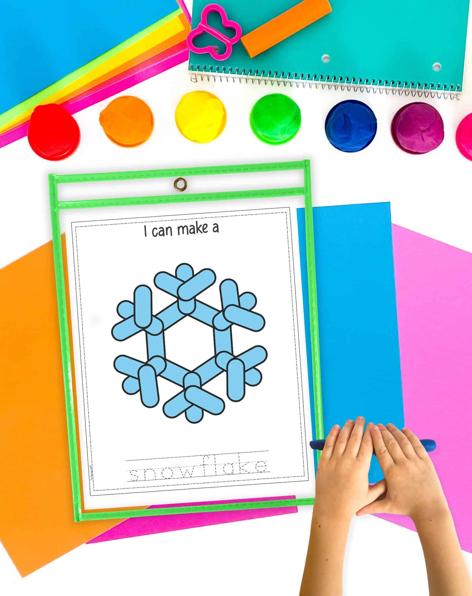 a snow flake play dough mat in a dry erase pocket with a child's hands rolling out a play dough snake