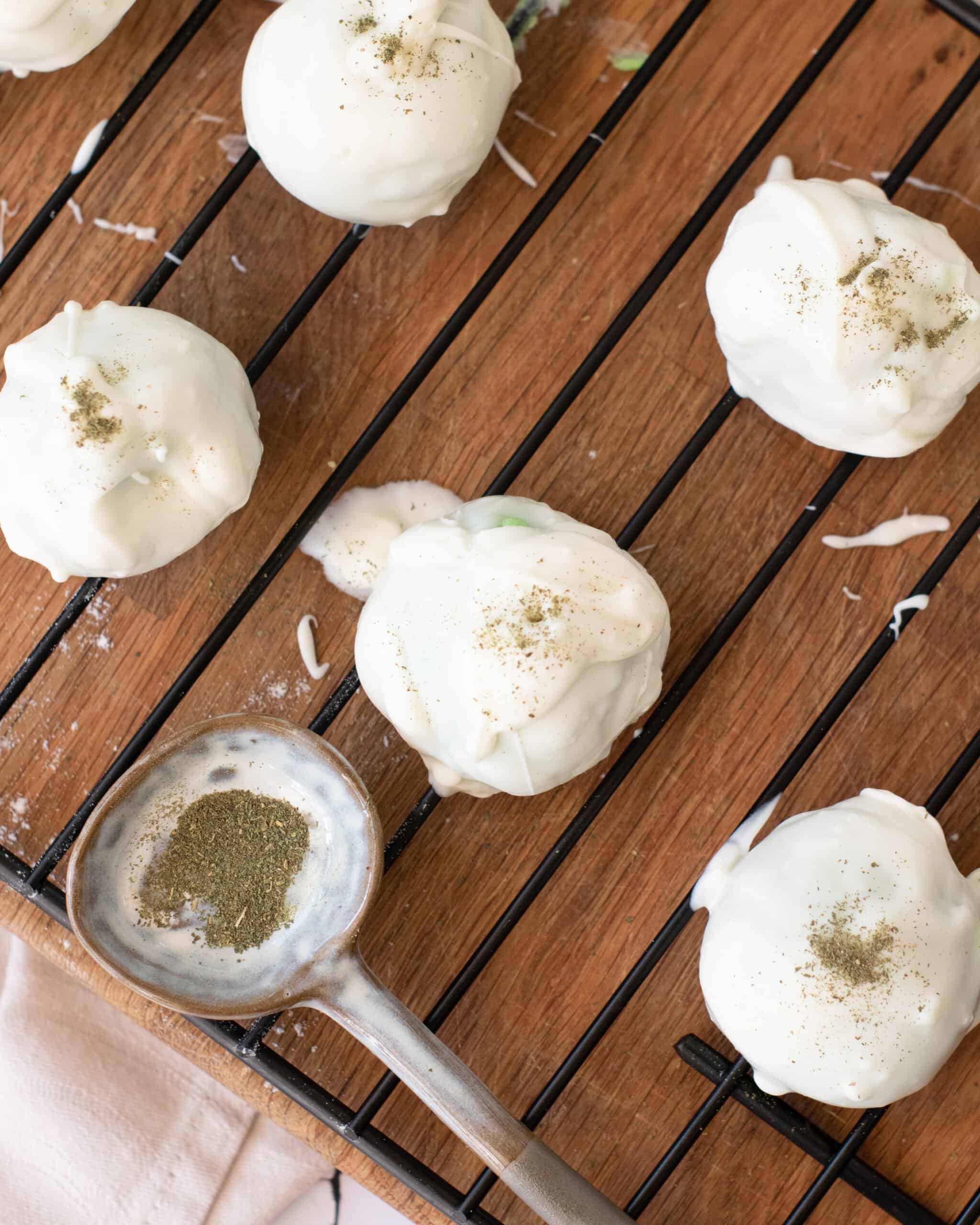 white chocolate truffles on a wire rack being sprinkled with matcha powder