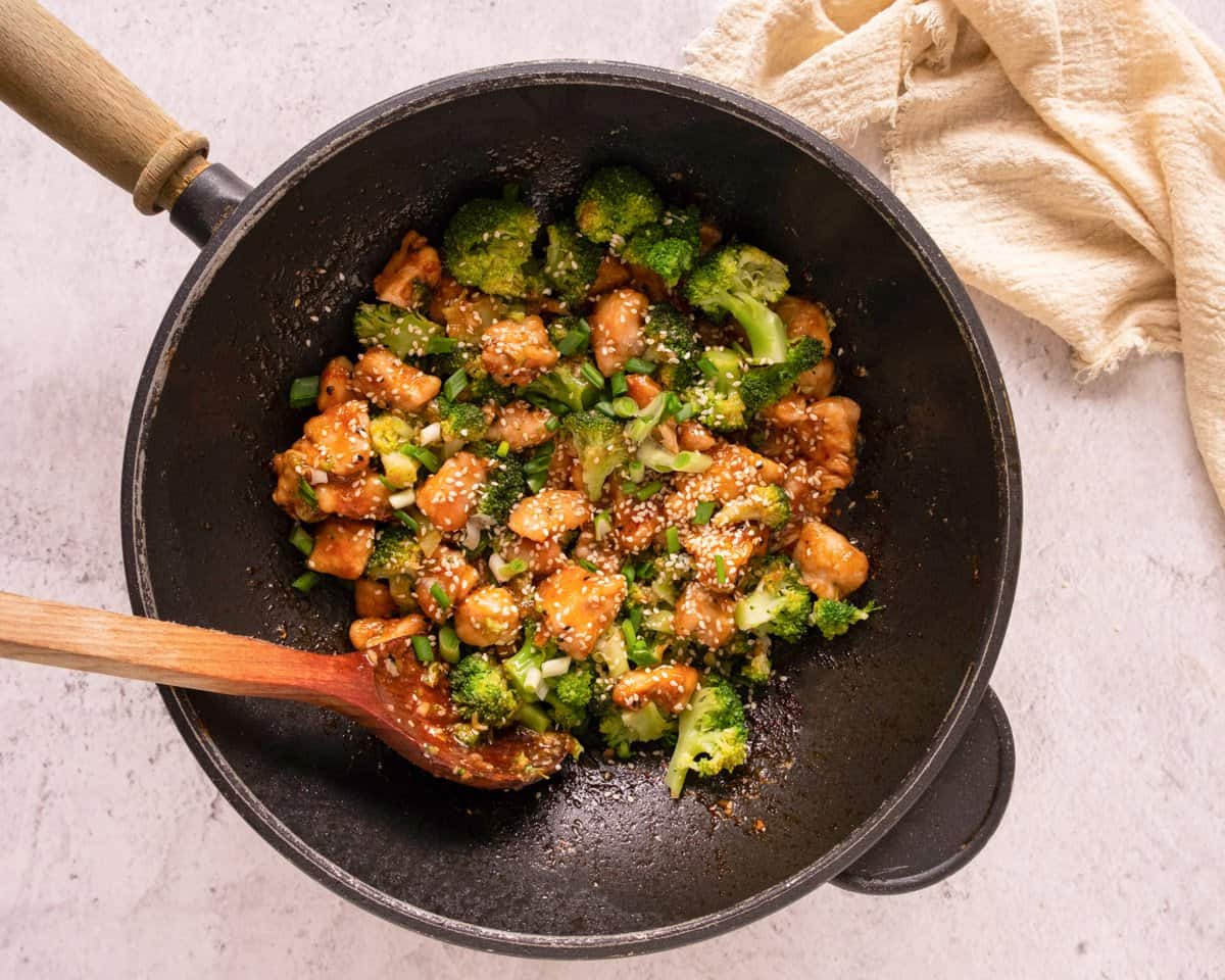 stirring broccoli into a skillet with chicken