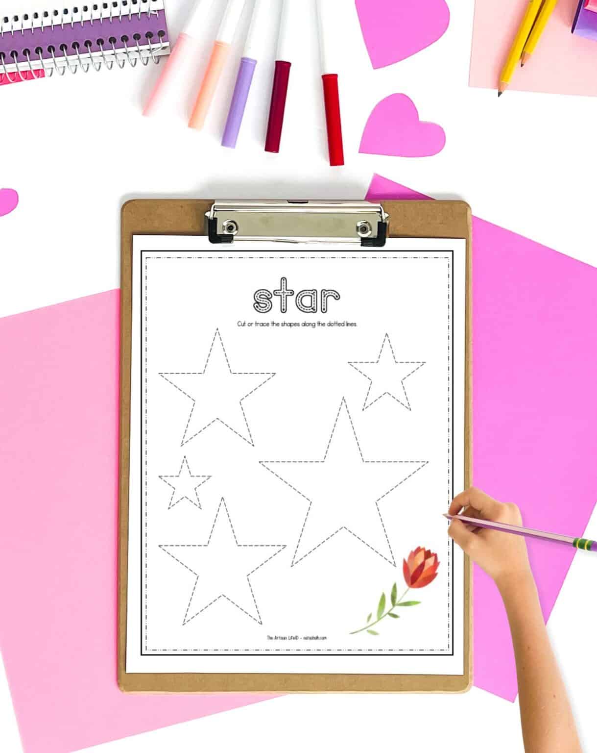 A Valentine's Day star tracing page on at table with pink papers and markers