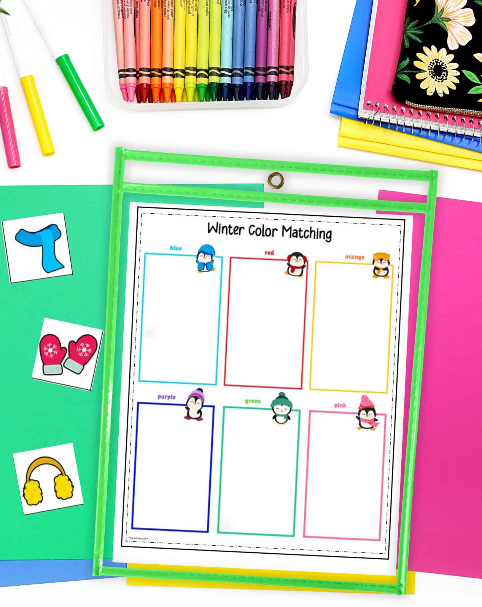 a winter color matching printable in a dry erase pocket. The printable is on a table with brightly colored papers