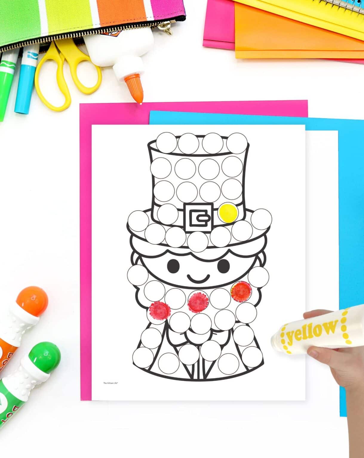 a partial completed leprechaun dot marker page on a table with colorful papers and markers