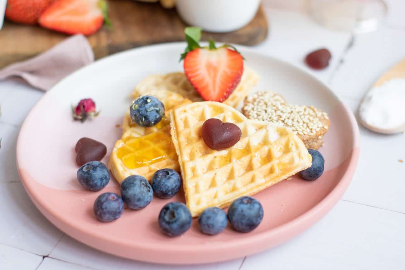 heart shaped waffles on a plate with blueberries and strawberries