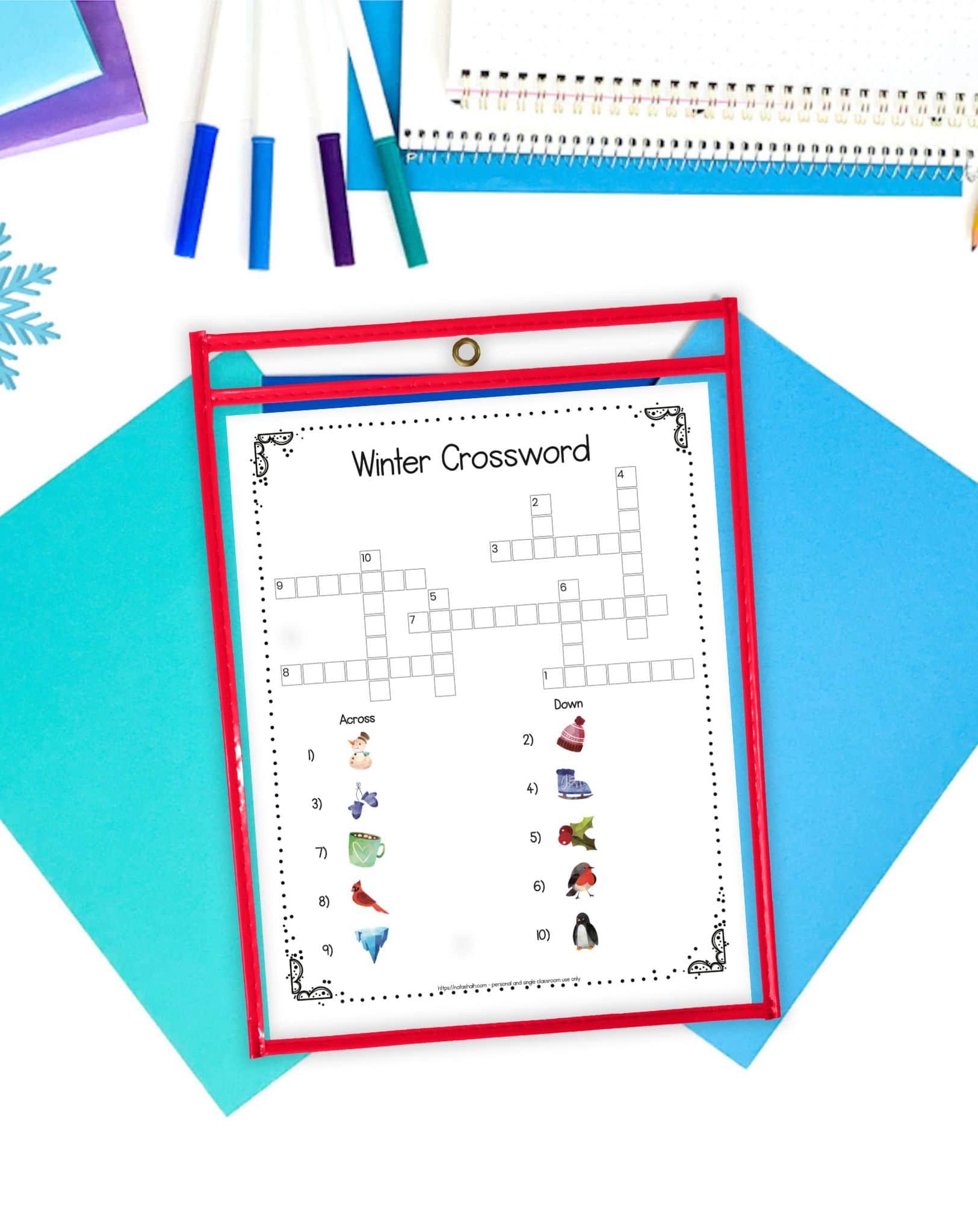 a winter picture crossword puzzle in a dry erase pocket on a desk with blue papers and markers