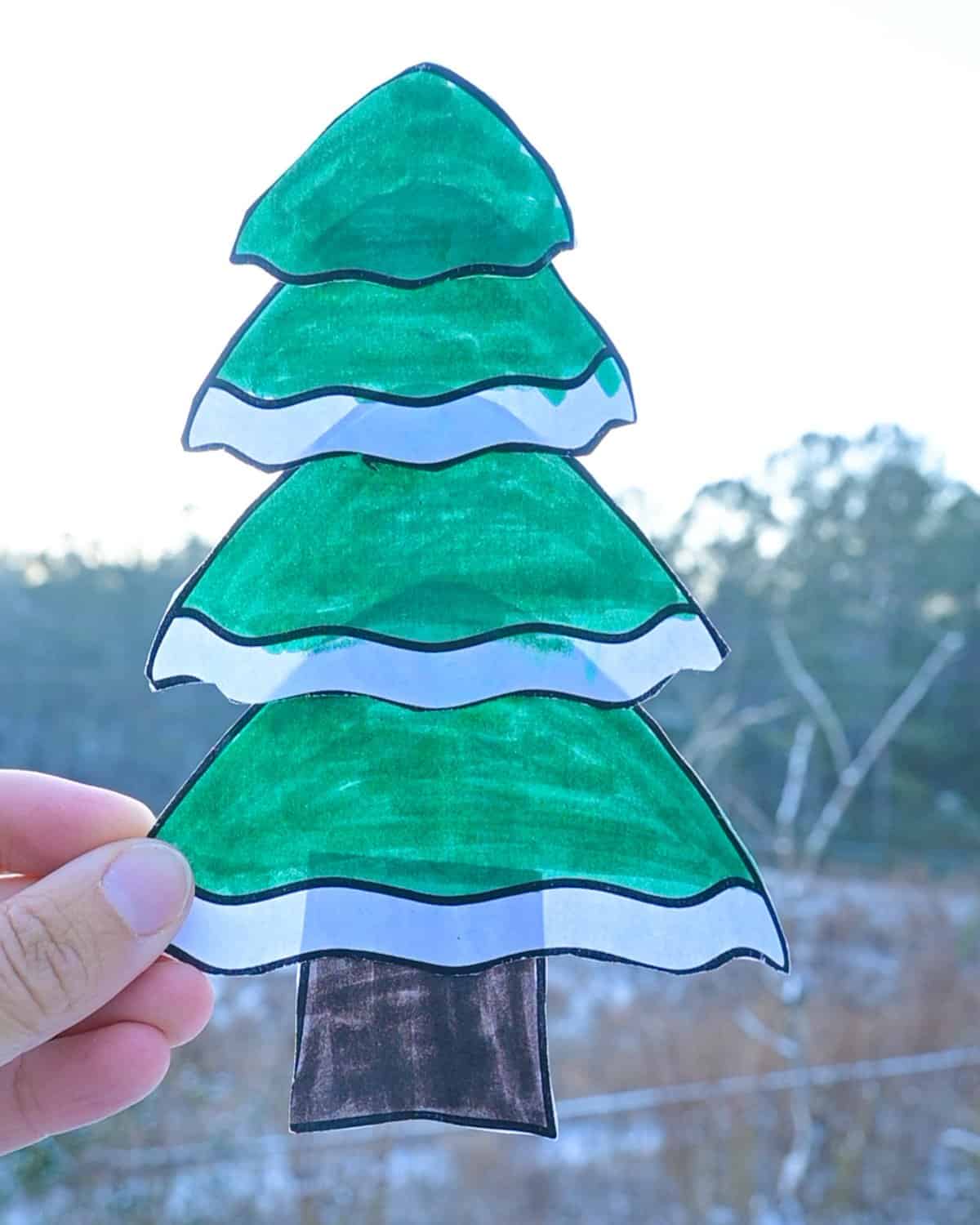 a hand holding up a completed water tree craft for kids