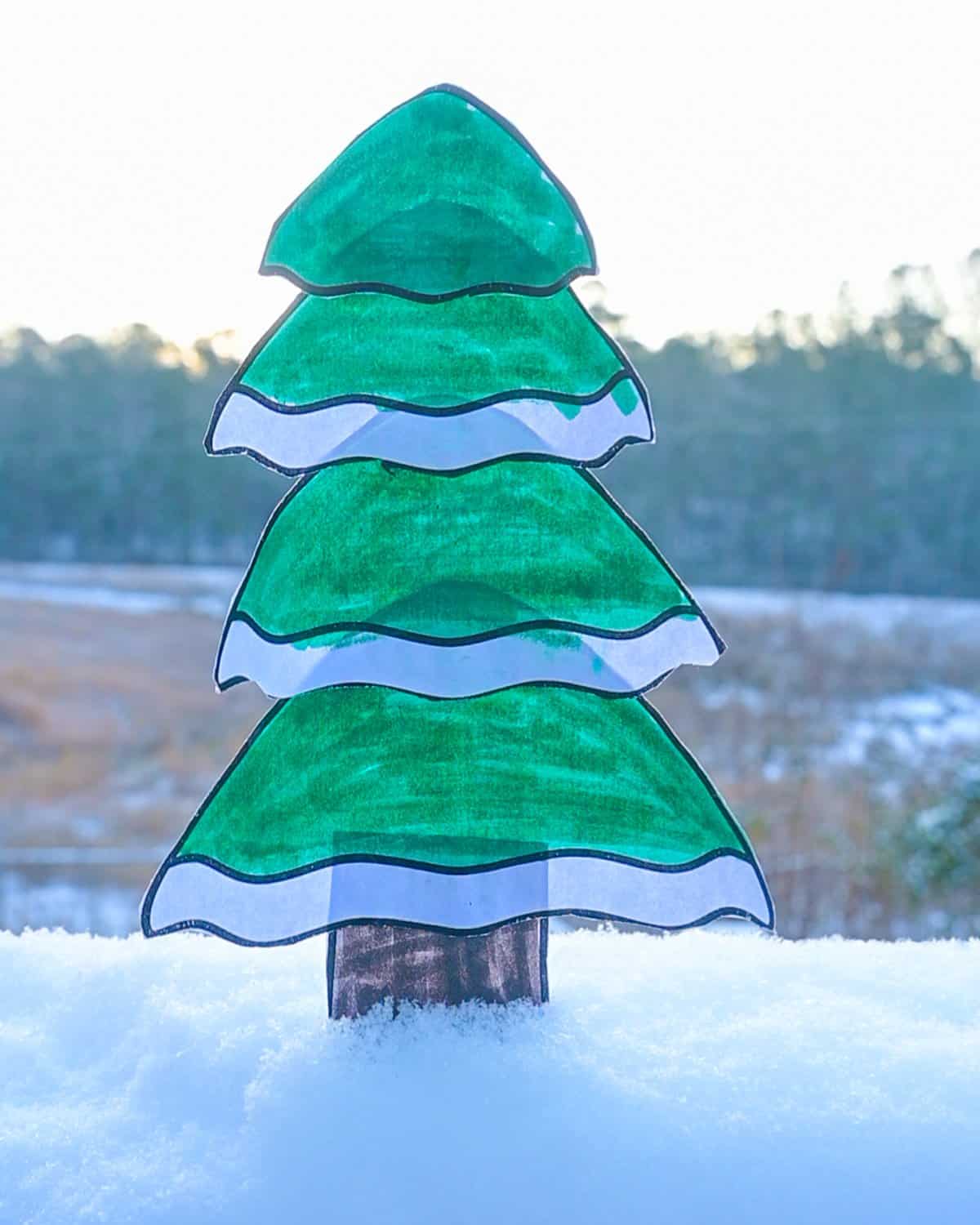 a colored and cut out cut and paste craft showing a tree with snow on it