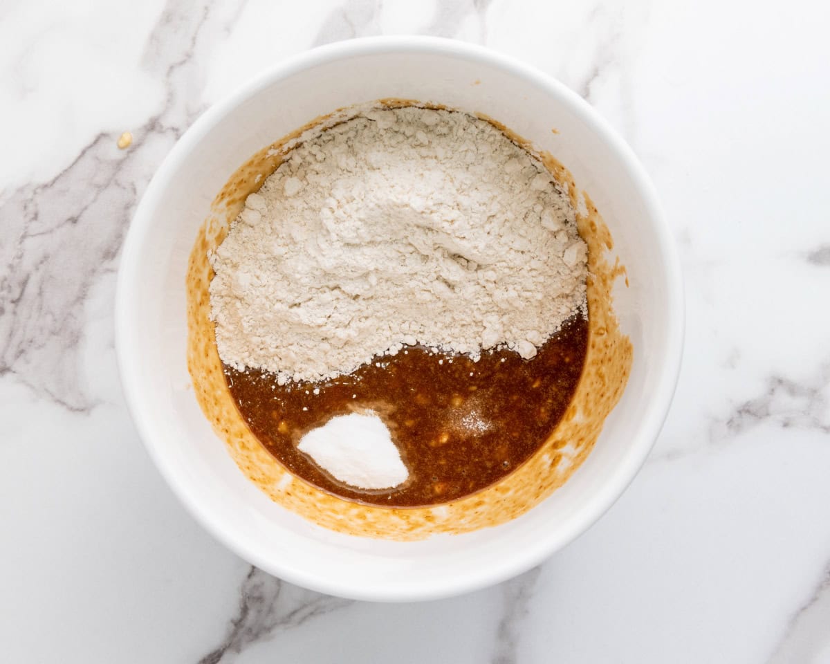 adding dry ingredients to mashed bananas and wet 