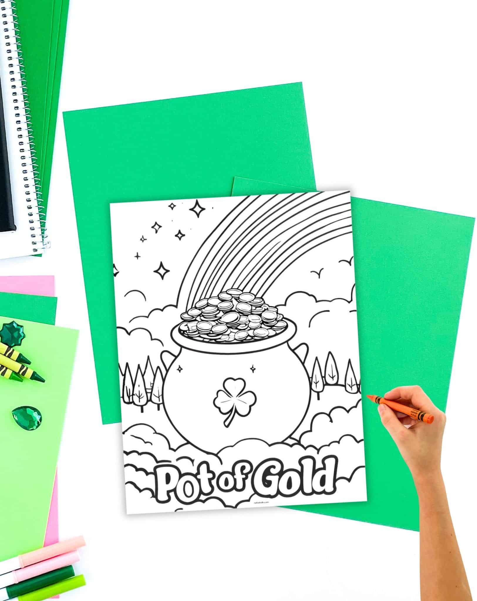 a pot of gold coloring page on a table with green papers and crayons