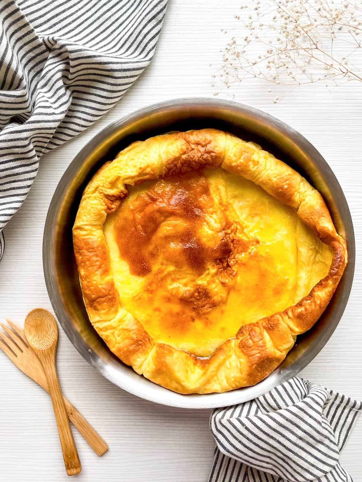 a crispy baked Dutch baby pancake in a stainless steel pan