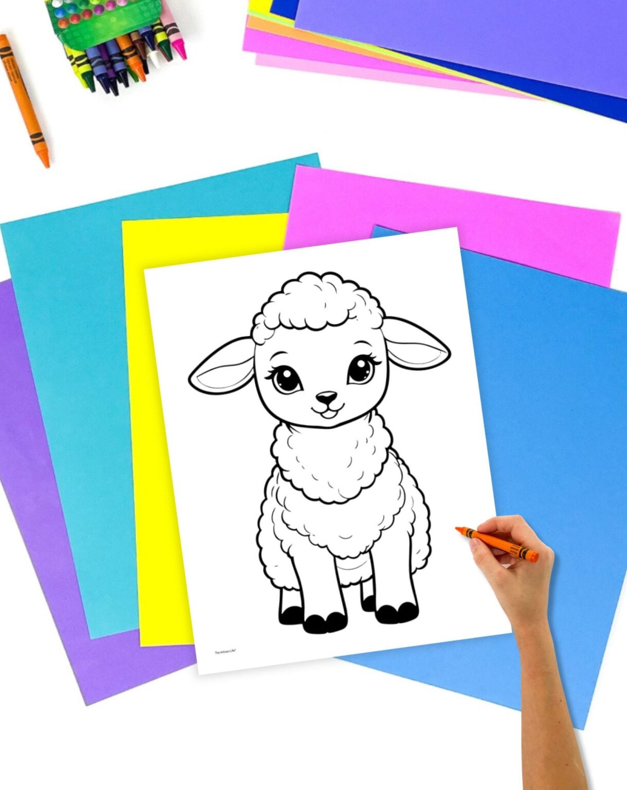 A hand is holding an orange crayon, positioned near a black-and-white coloring page of a cute lamb, surrounded by colorful sheets of paper, suitable for Easter-themed activities or children’s crafts.