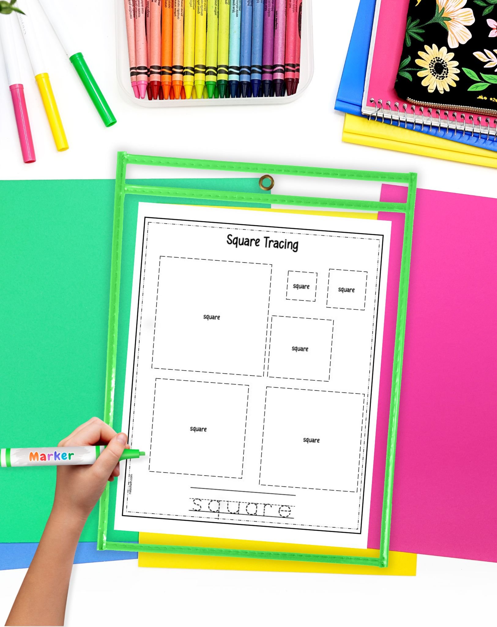 A hand holding a green marker traces squares on a worksheet titled "Square Tracing," surrounded by colorful paper and a container of crayons, illustrating square activities for preschool learning.
