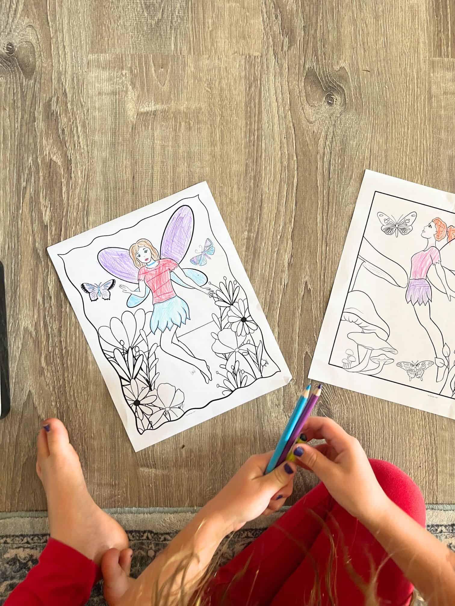 A top down photo of a young child coloring a fairy coloring page