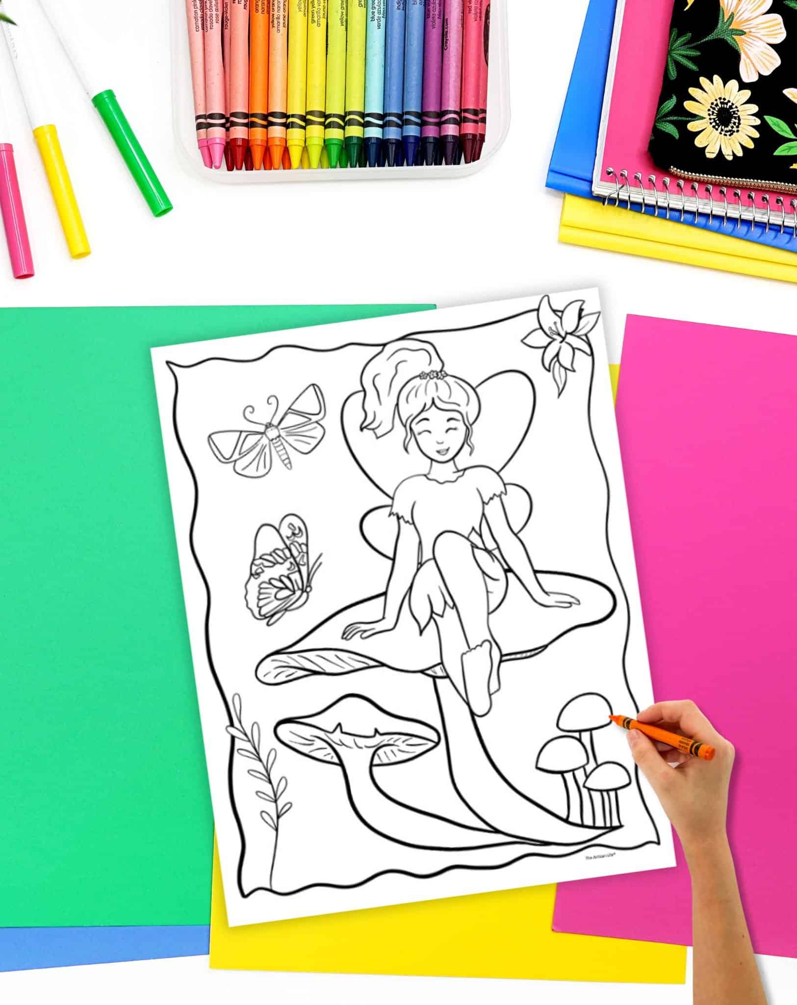 A coloring page with a fairy sitting on a mushroom. A hand holding an orange crayon is ready to start coloring.