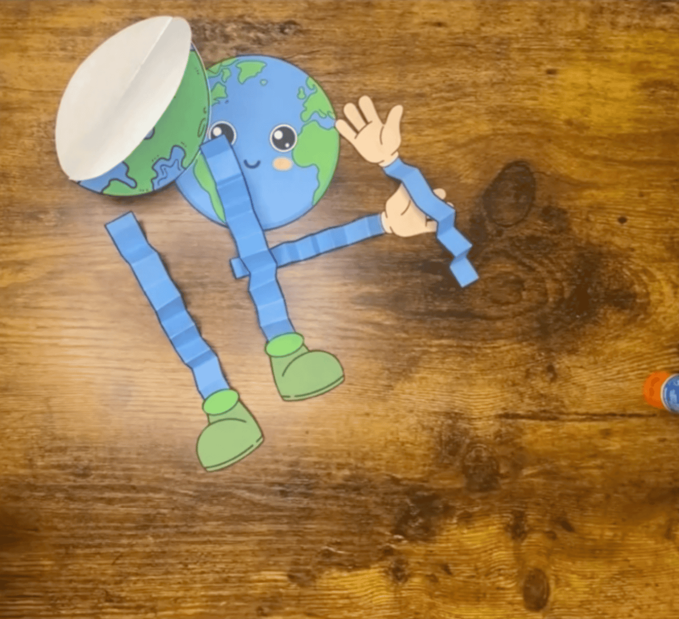 An arrangement of cut-out Earth templates, green boots, blue strips, and handcutouts, suitable for easy Earth Day crafts for kids and preschool activities.
