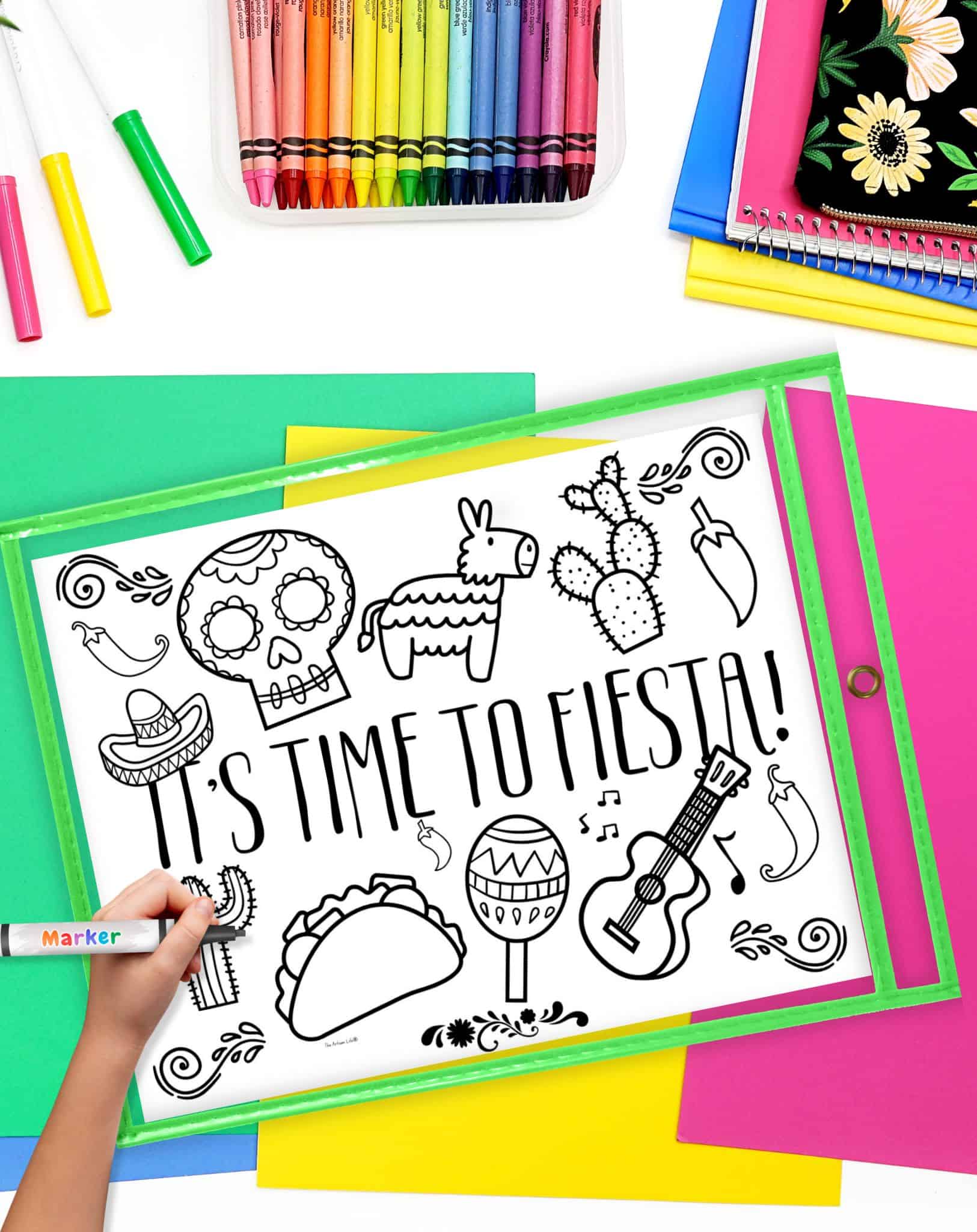 A child's hand colors a Cinco de Mayo-themed coloring page featuring festive images such as a piñata, sombrero, and taco, surrounded by colorful stationery and craft supplies, highlighting activities for kids like fiesta crafts and homeschooling resources.
