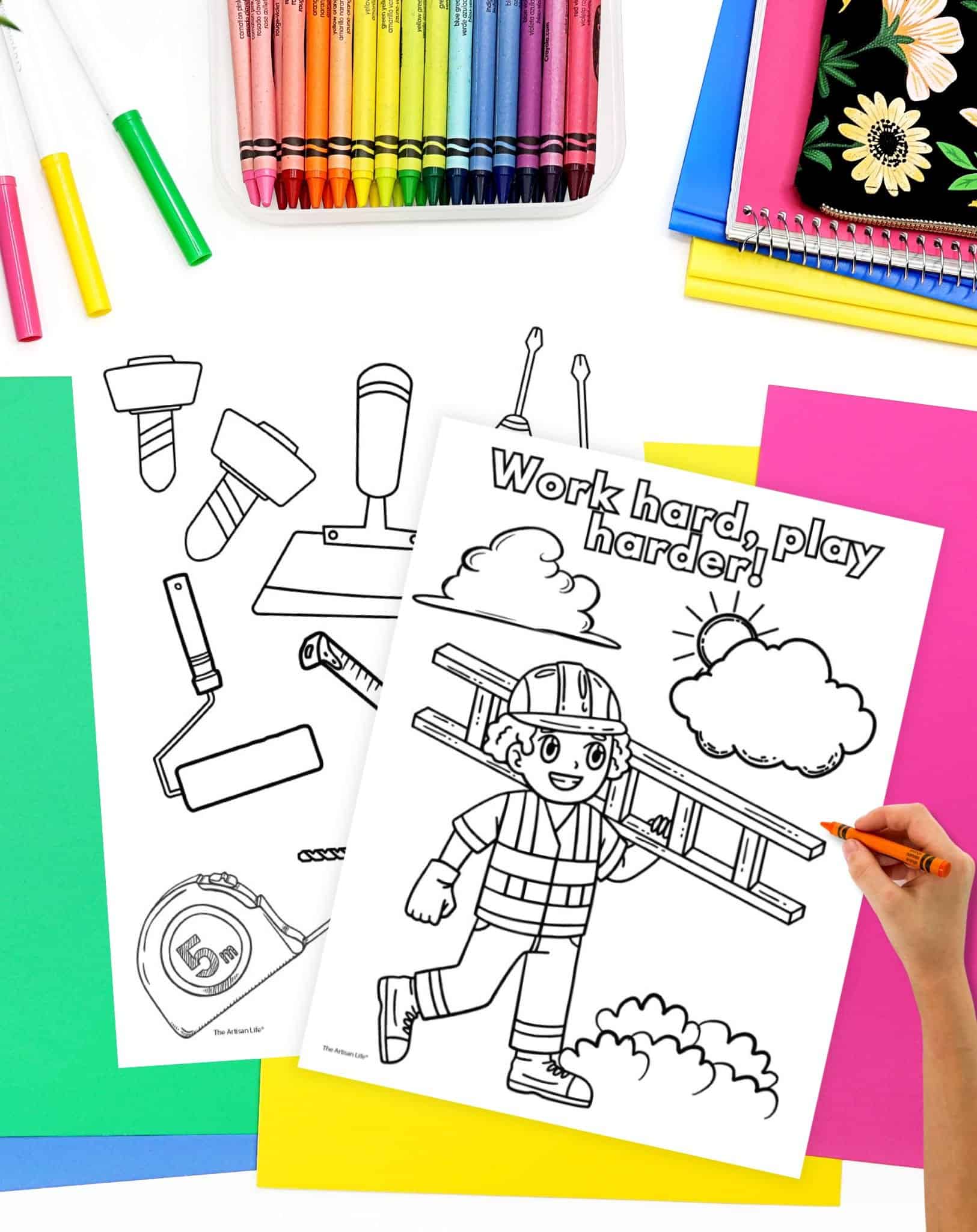 A hand colors a construction-themed coloring page featuring a child with a ladder, surrounded by other uncolored construction tools and colorful crayons on a bright workspace.
