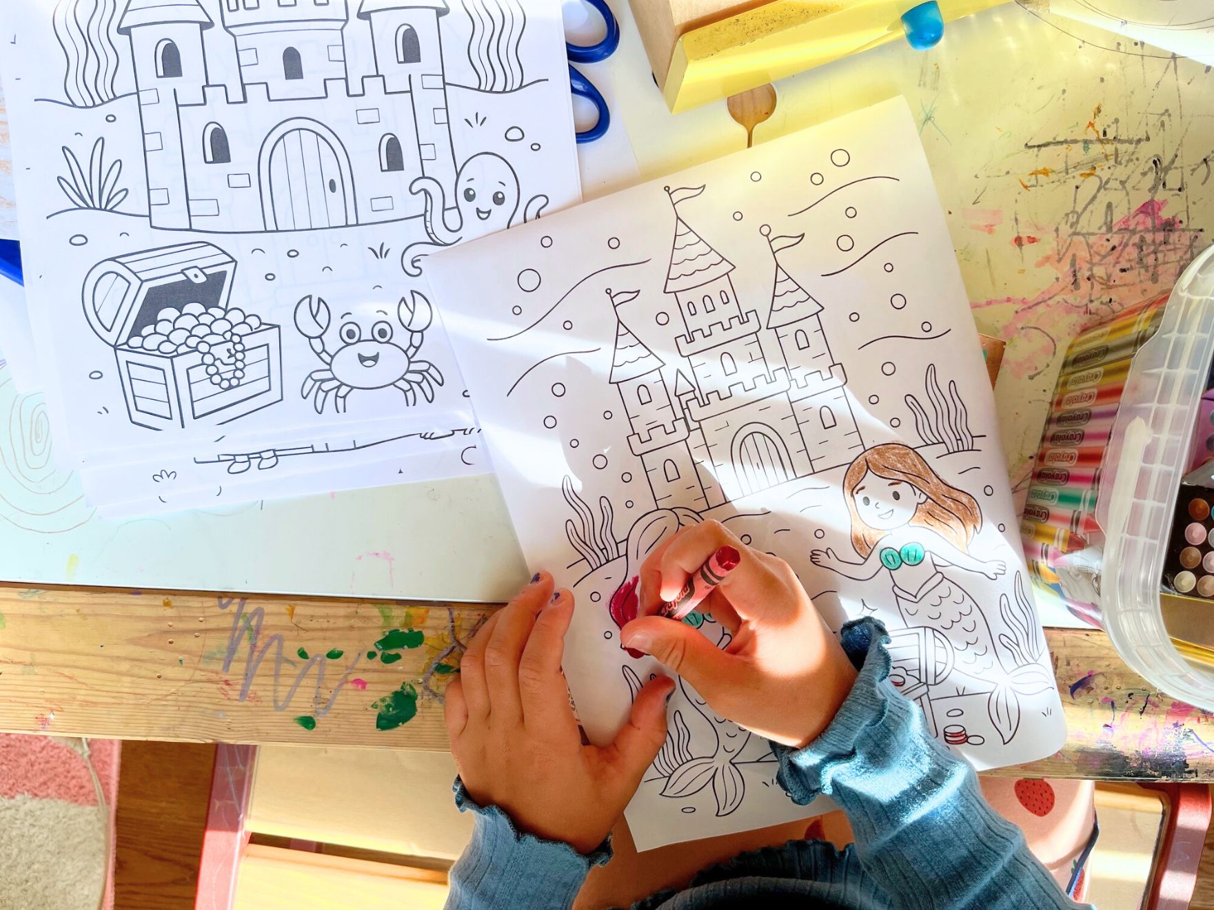 A child coloring a coloring page with a castle and mermaids