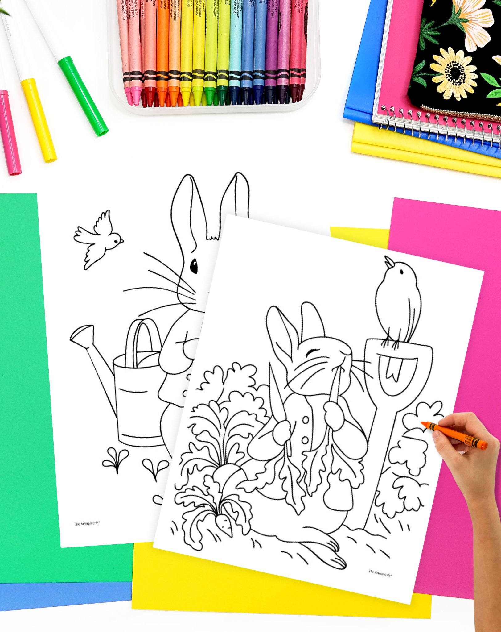 Two Peter Rabbit coloring pages on a desk with brightly colored papers and markers