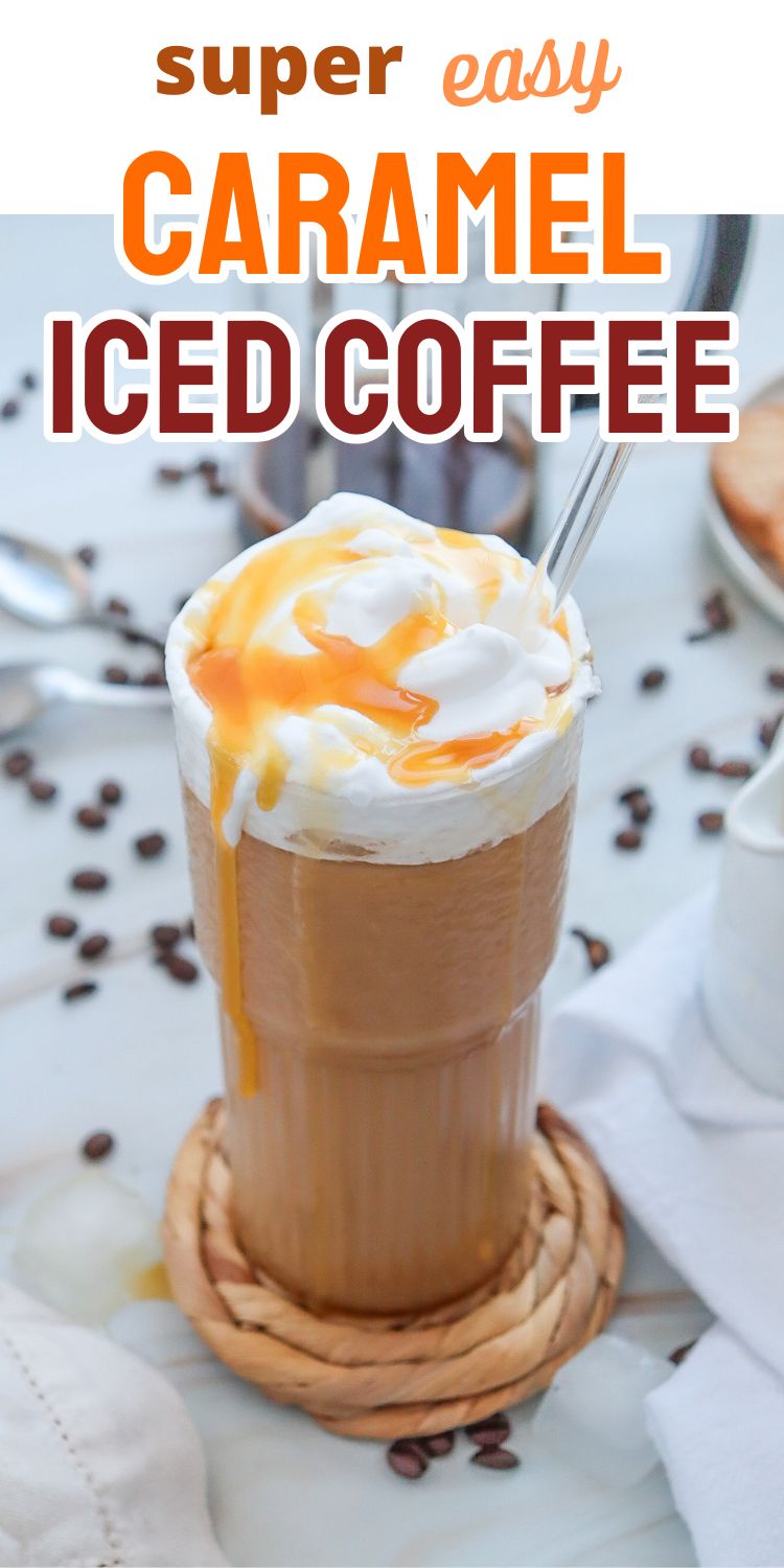 A tall glass of caramel iced coffee topped with whipped cream and caramel syrup is displayed on a woven coaster, surrounded by coffee beans and ice.
