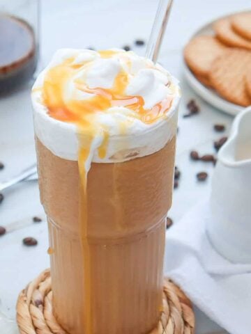 a glass with iced caramel coffee and whipped cream