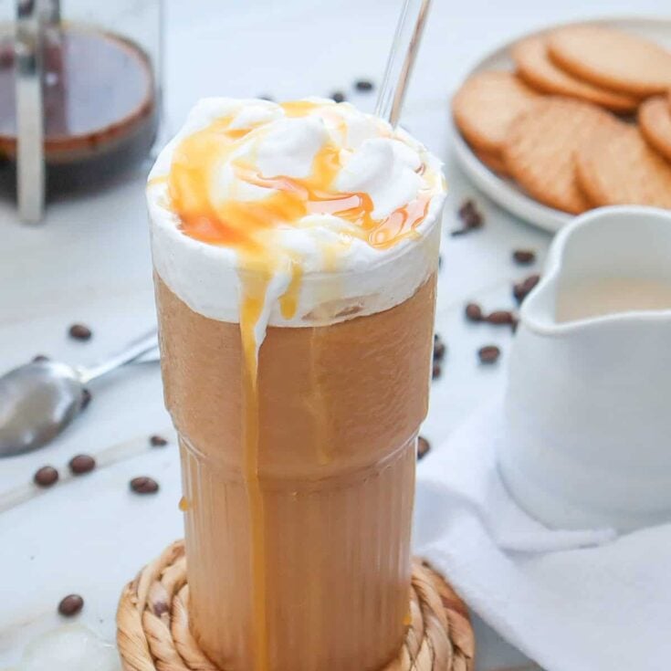 a glass with iced caramel coffee and whipped cream