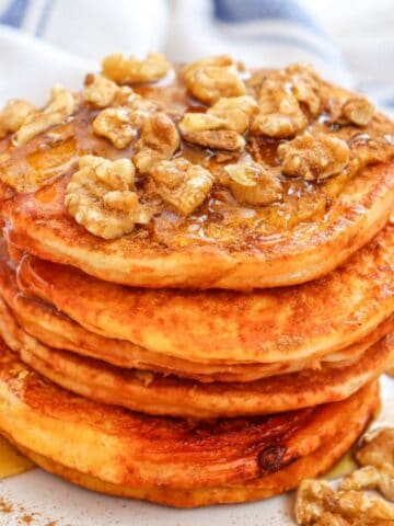 a stack of pumpkin pancakes with walnuts on top