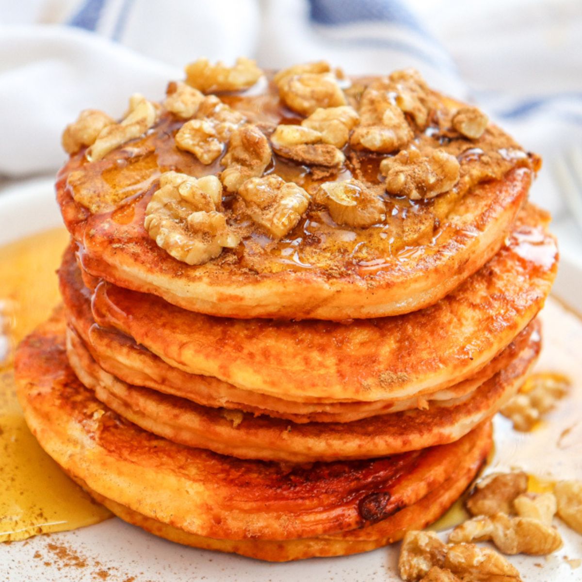 a stack of pumpkin pancakes with walnuts on top