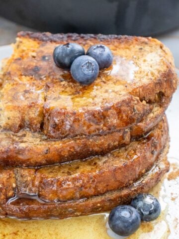 a stack of sourdough toast with maple syrup and blueberries