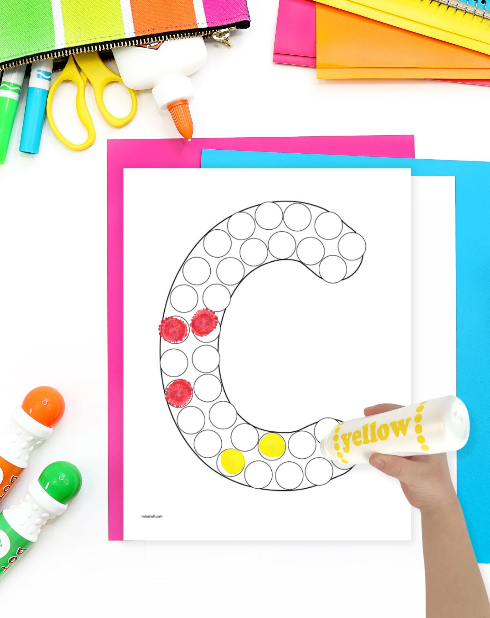 a child's hand with a yellow dot marker coloring a letter c dot marker coloring pages