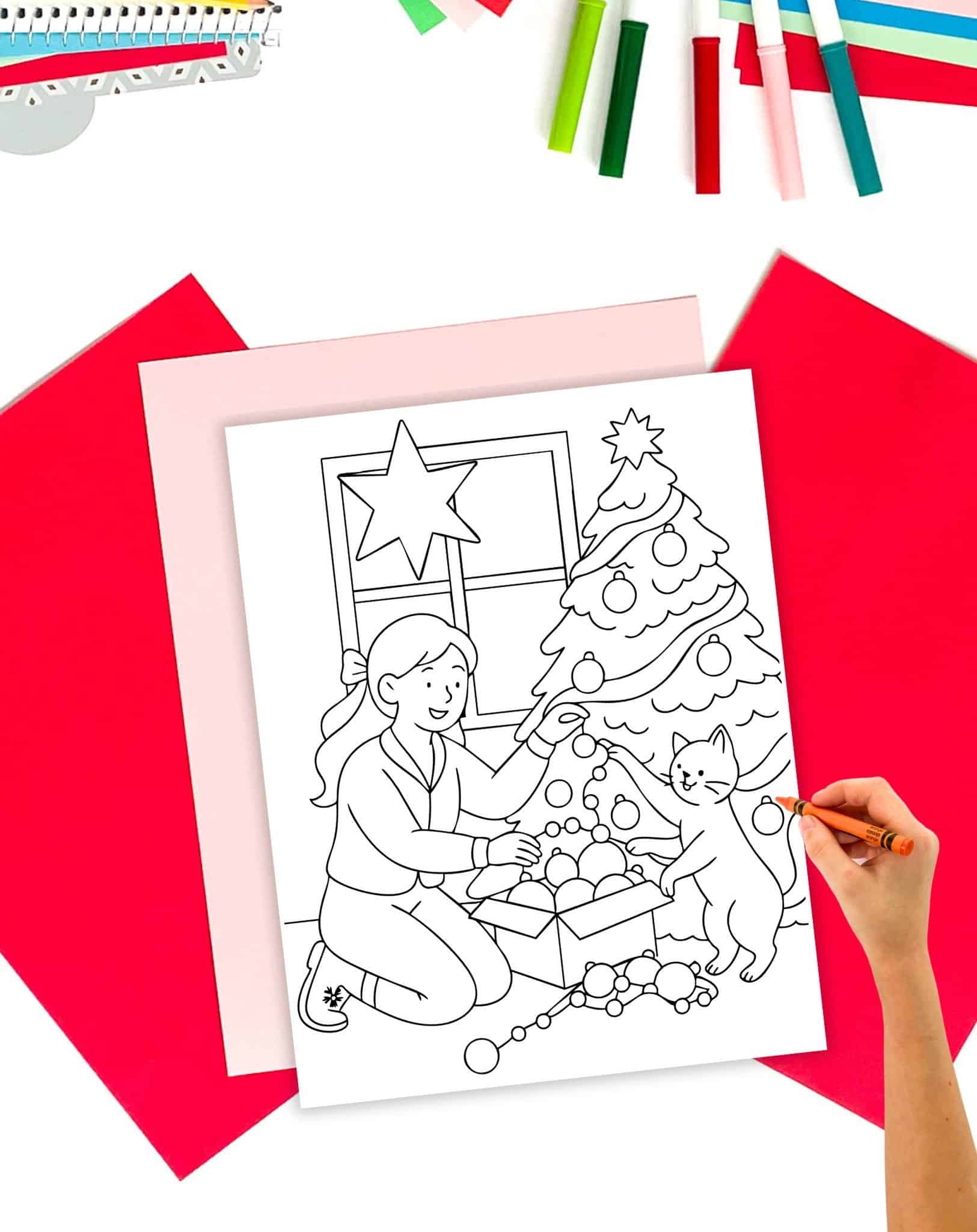 a hand coloring a coloring page showing a woman decorating a Christmas tree with her cat