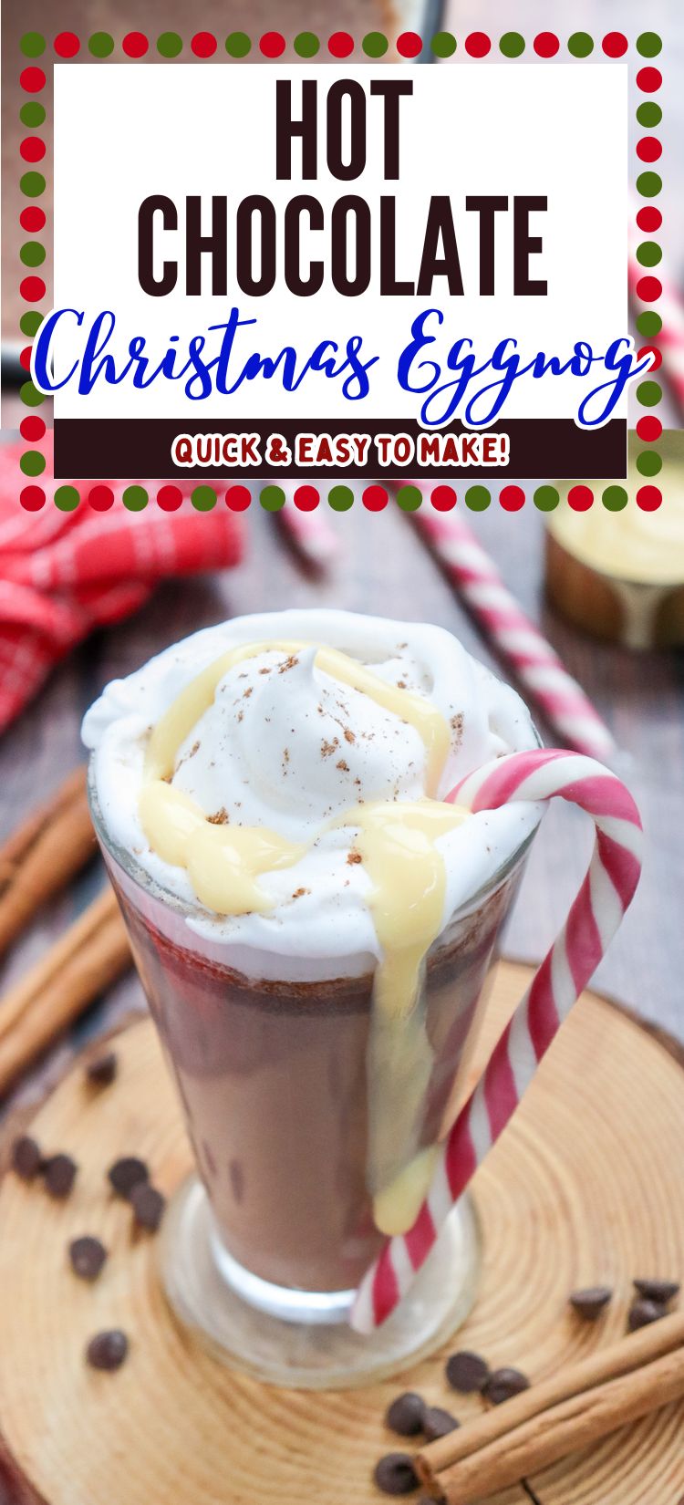 A glass of hot chocolate topped with whipped cream and yellow drizzle, accompanied by a candy cane, sits on a wooden platter surrounded by chocolate chips and cinnamon sticks.