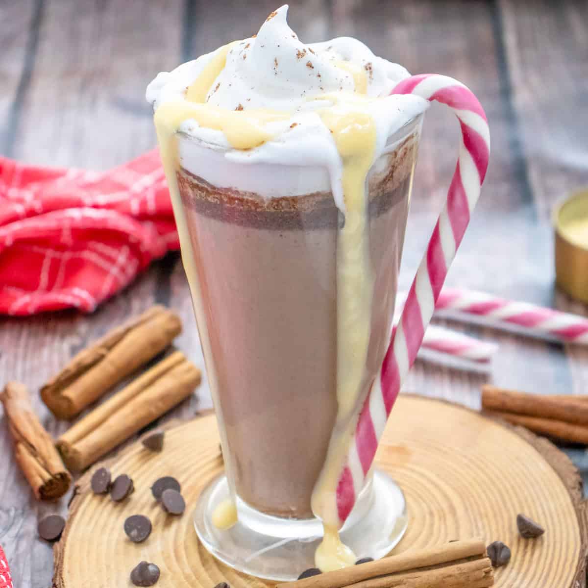 a glass mug with hot chocolate egg nog served with whipped cream and a candy cane
