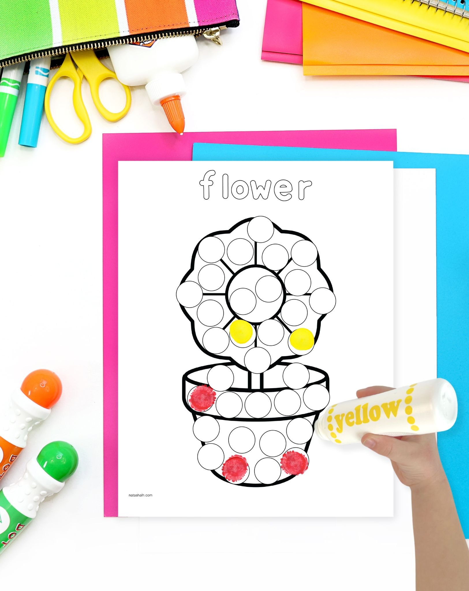 a child's hand with a yellow dot marker preparing to use a flower dot marker page for Valentine's Day