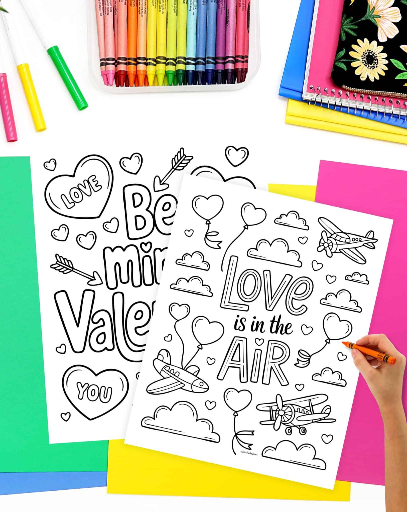a hand coloring a valentine's day coloring page with the words "love is int eh air" with balloons and airplanes