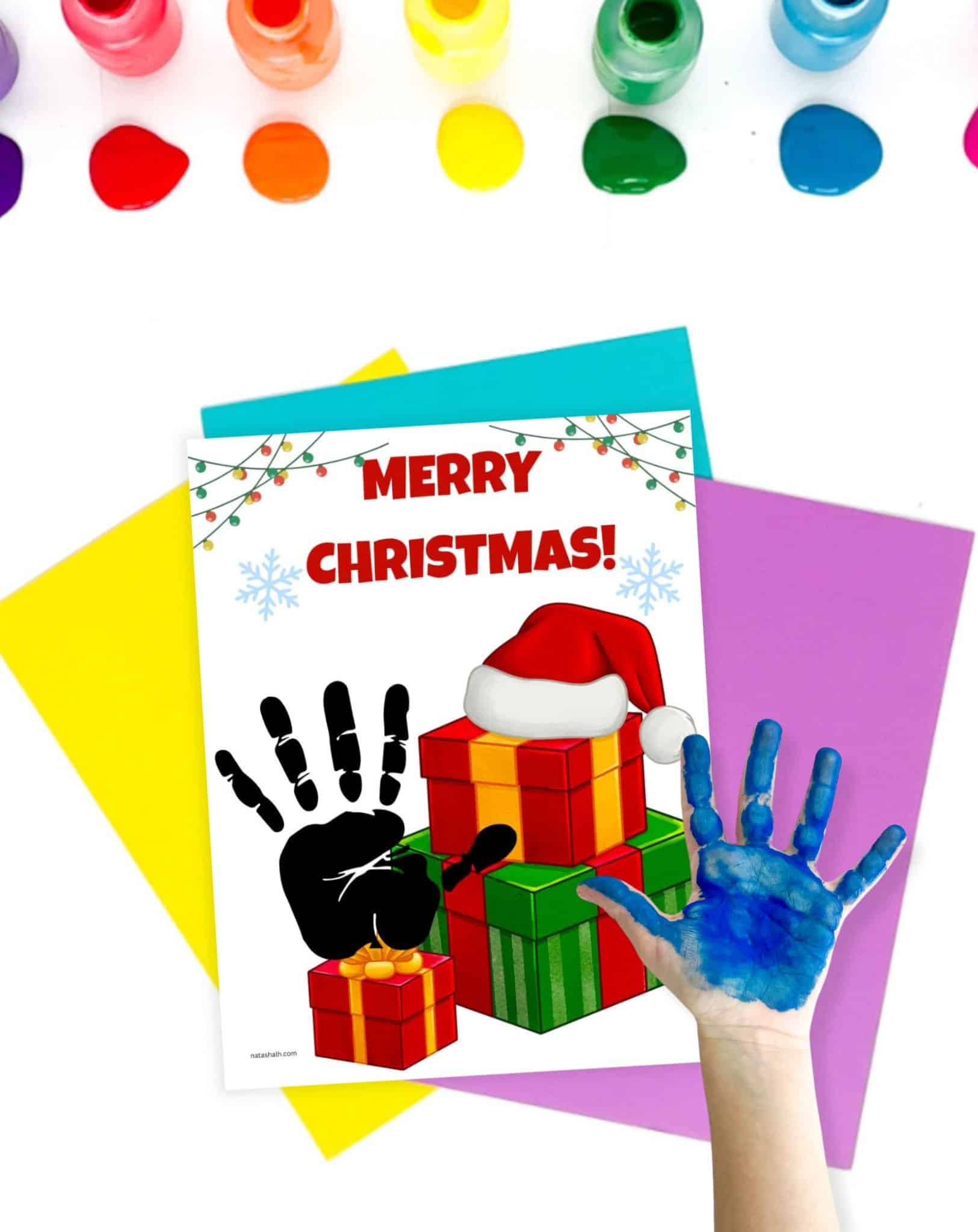 a child's painted hand completing a Christmas teemed handprint art craft