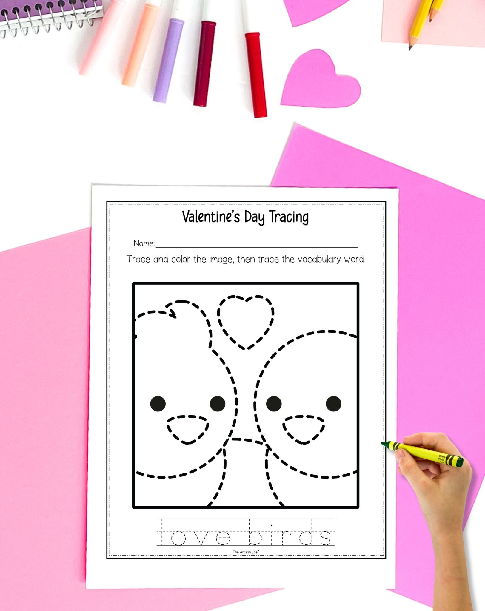 a hadn't holding a cray0on preparing to use a valentine's day trace and color page showing two birds