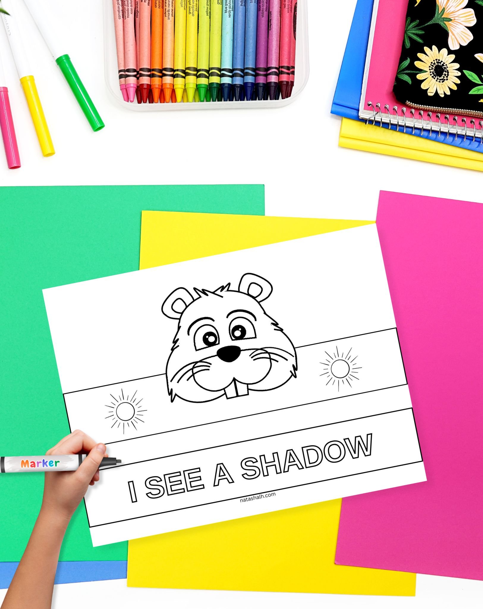 a child with a crayon coloring a Groundhog Day crown craft