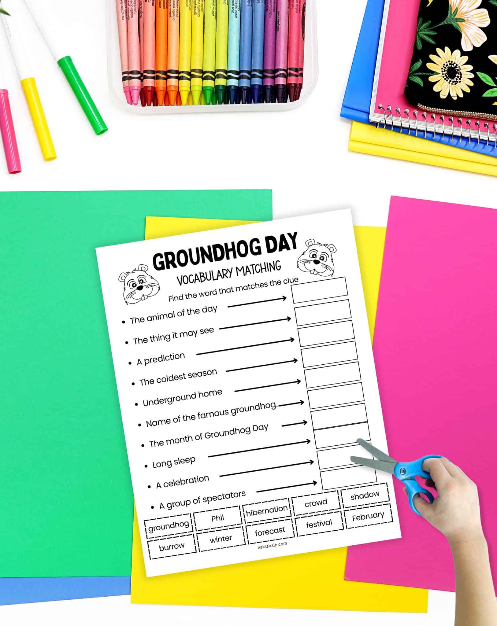a child's hadn't with scissors preparing to use a Groundhog Day cut and paste vocabulary worksheet