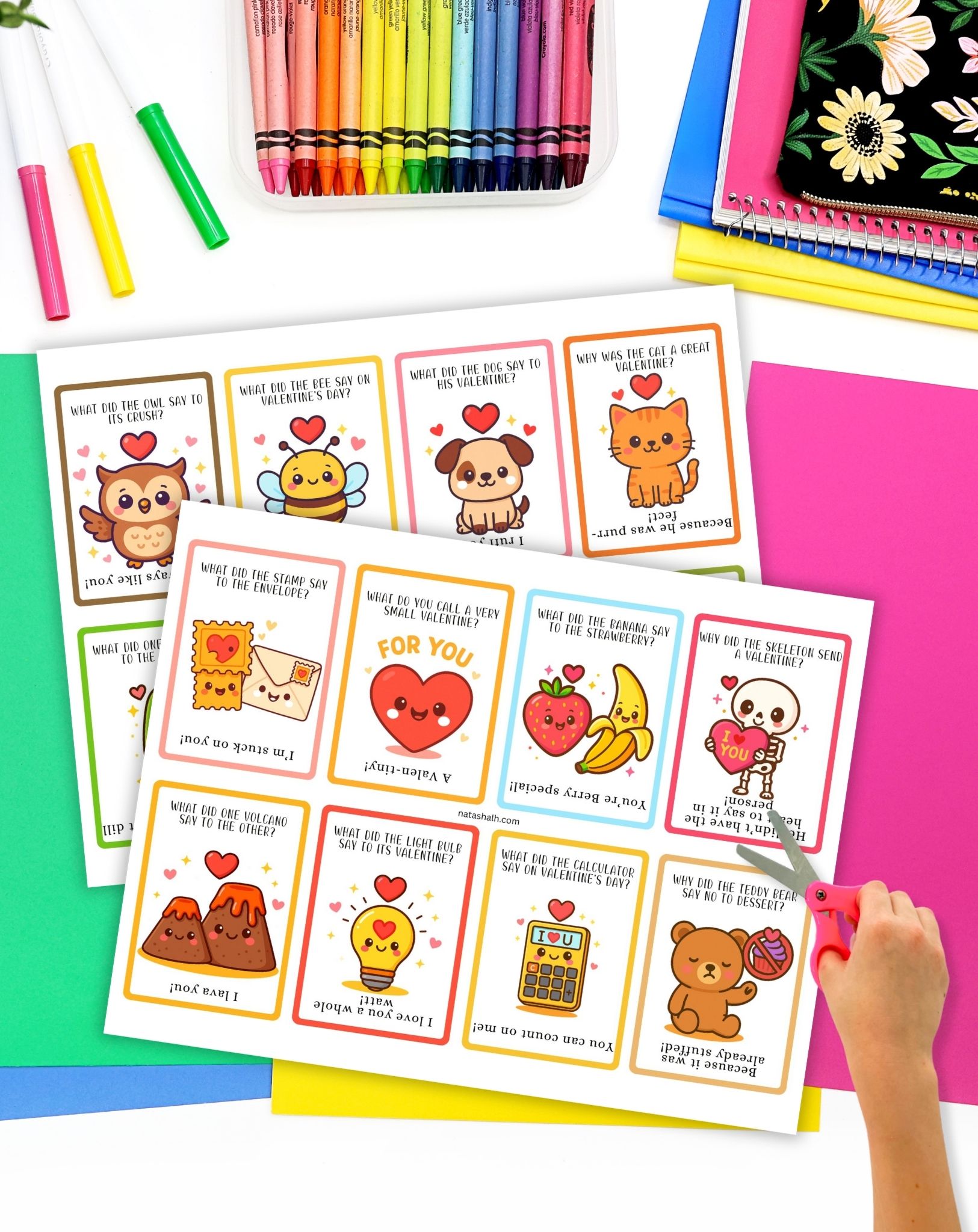 a child's hand with scissors preparing to cut apart printable valentines day cards