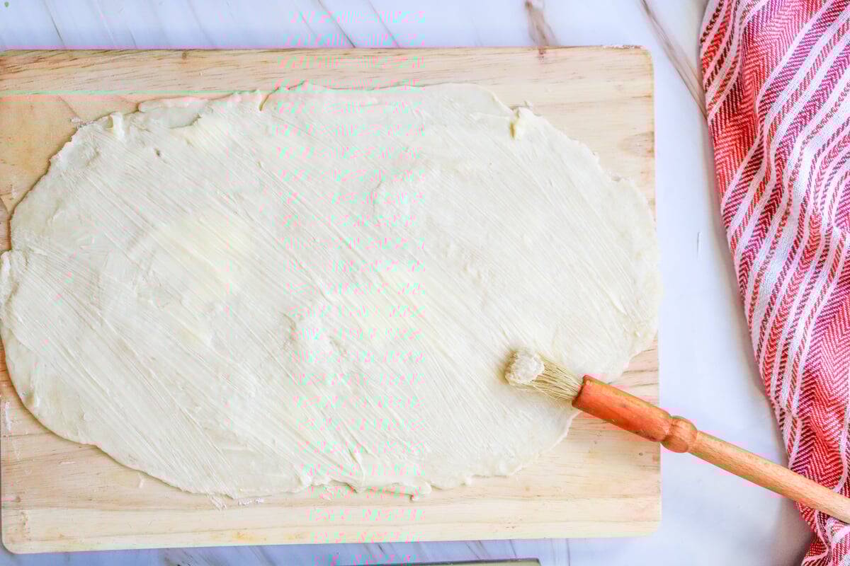 Buttering a spread sheet of dough for cinnamon rolls