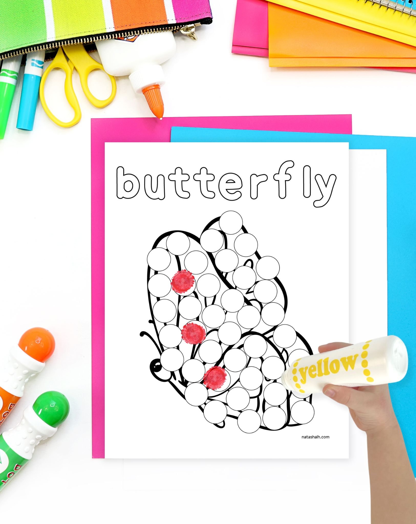 a child's hand with a dauber marker preparing to color a butterfly dot marker coloring page