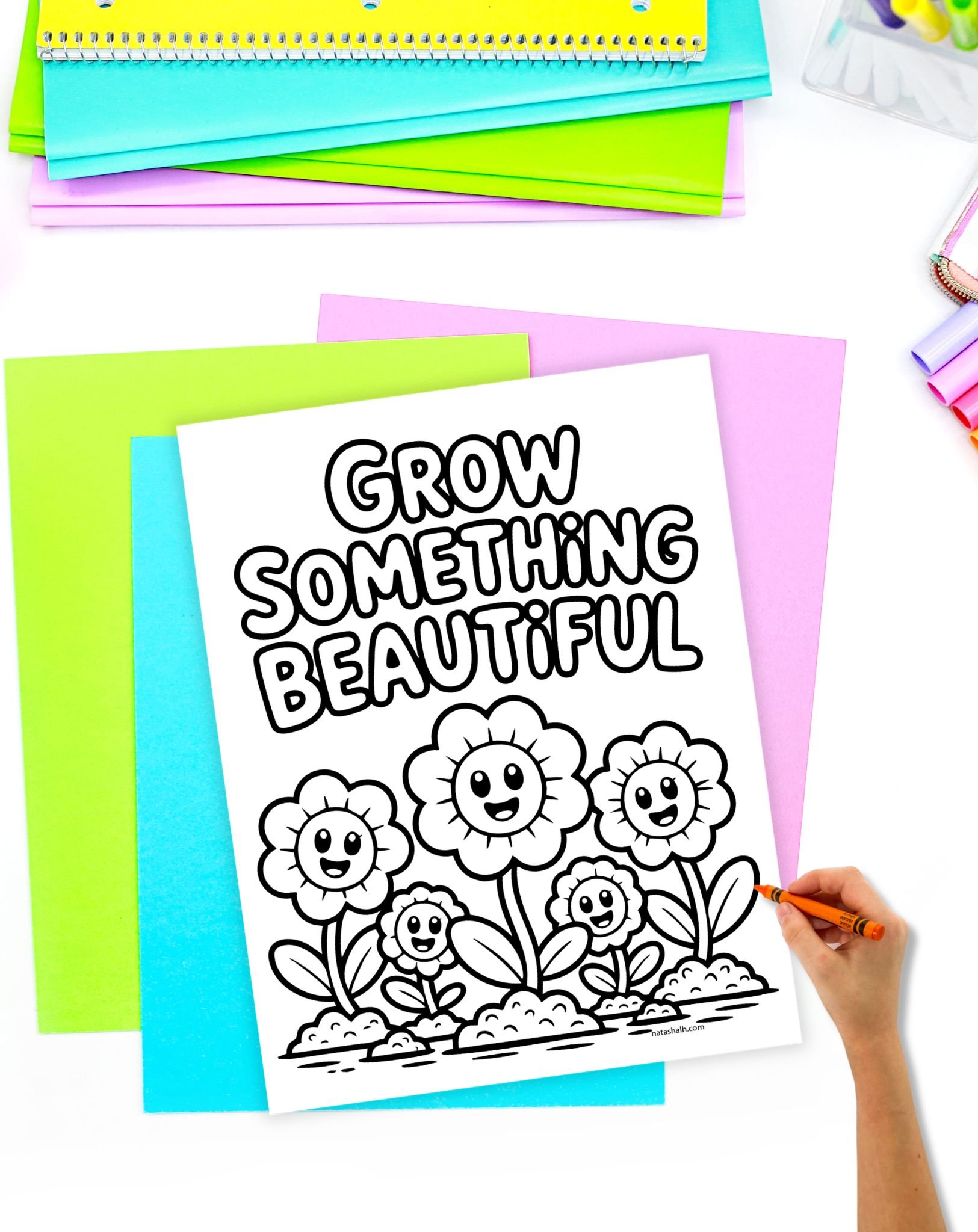 a child's had with a crayon preparing to color an easy coloring page with flowers