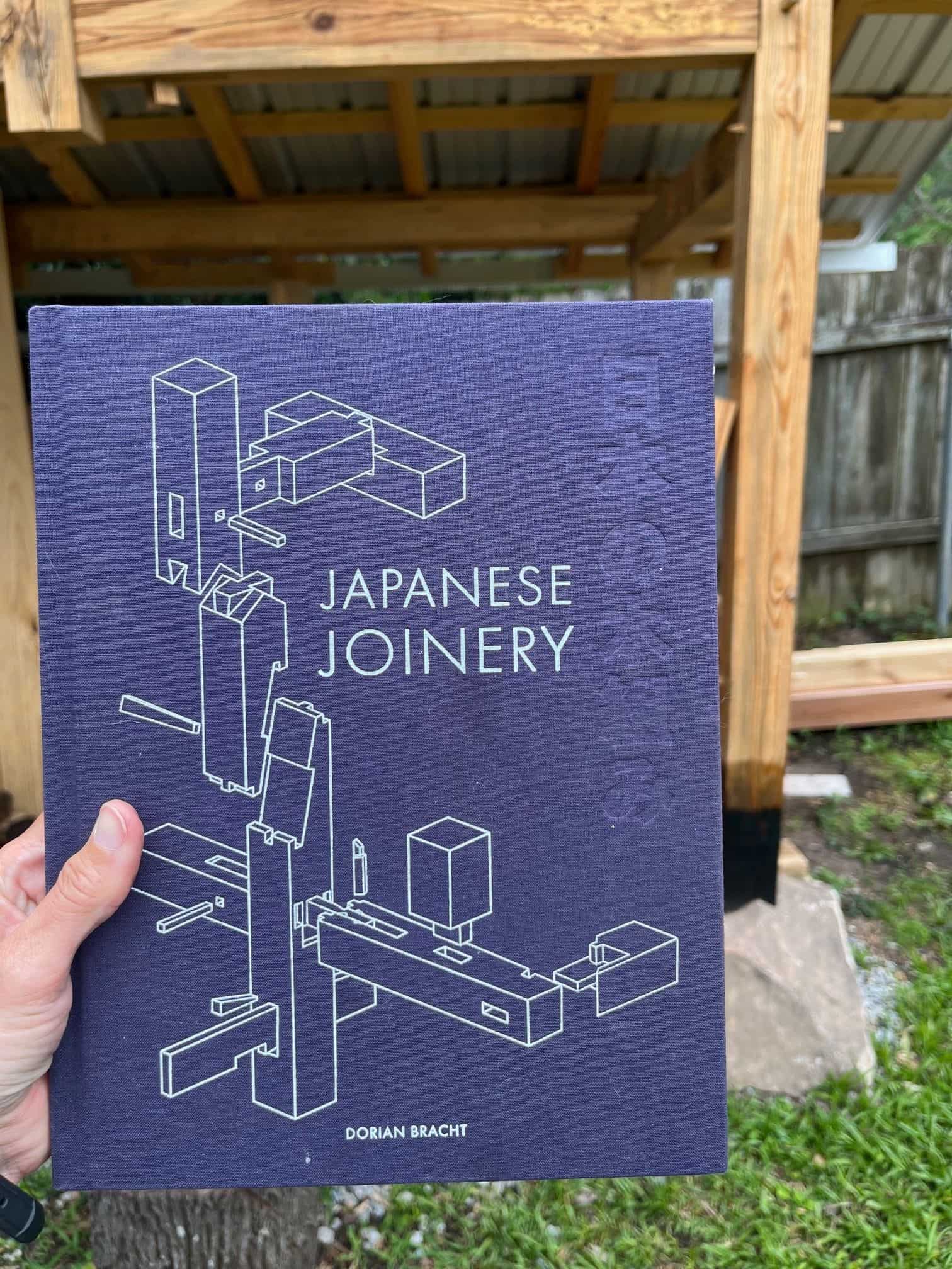 a hand holding a book called "japanese joinery"
