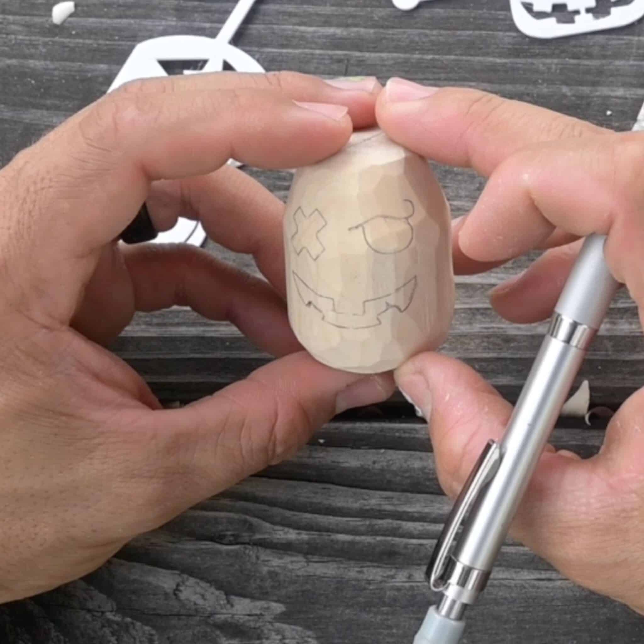 a face traced on a block of wood to carve a wood jack o lantern